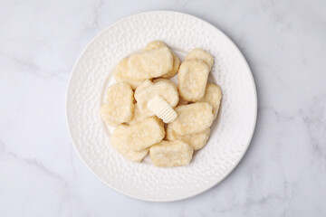 Plate of tasty lazy dumplings with butter on white marble table, top view