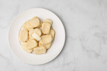 Plate of tasty lazy dumplings with butter on white marble table, top view. Space for text