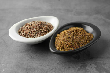 Caraway (Persian cumin) powder and dry seeds on gray table