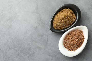 Caraway (Persian cumin) powder and dry seeds on gray table, top view. Space for text