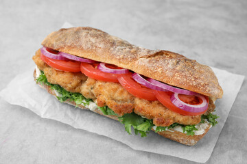 Delicious sandwich with schnitzel on grey table, closeup