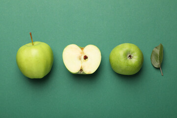 Whole, cut green apples and leaf on color background, flat lay