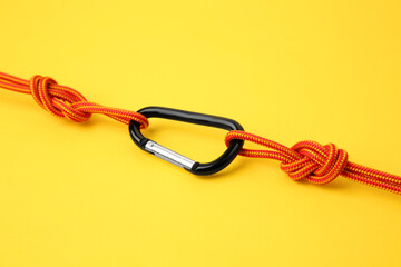 One metal carabiner with ropes on yellow background