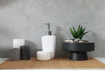 Potted artificial plant, liquid soap, decor and bamboo mat on bathroom vanity