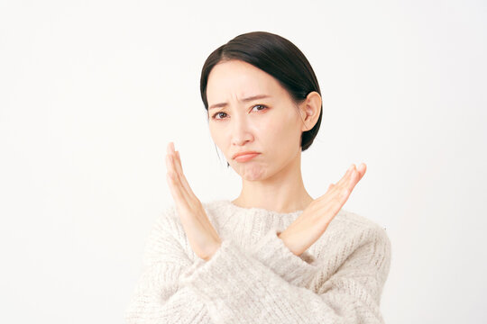 腕でばつ印のジェスチャーをする中年女性　白背景