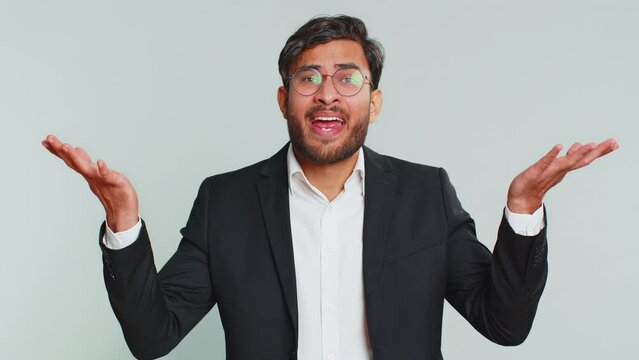 What. Why. Angry Indian businessman raising hands in indignant expression, asking reason of failure demonstrating disbelief irritation by troubles. Arabian young man isolated on gray studio background