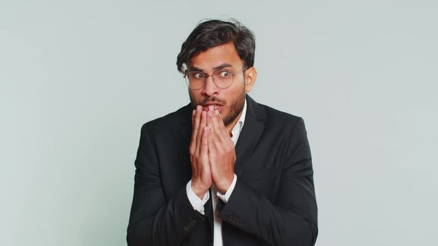 Stressed depressed Indian businessman terrified about danger problems, suffering phobia, anxiety disorder, expresses fear, waving no, insecure, stress, panic. Scared fearful man on gray background