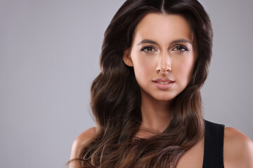 Naklejka premium Gorgeous woman with shiny wavy hair on grey background, space for text. Professional hairstyling