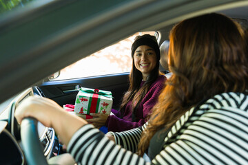Happy women friends driving to go shopping during christmas