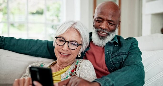 Old couple on sofa with phone, smile and relax with love, interracial marriage and bonding in home. Social media meme, mobile app and smartphone, happy senior man and woman on couch in living room.
