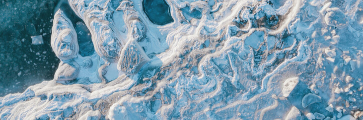 Top view of the icy seashore. Winter aerial photograph of ice floes on the sea coast. Amazing...