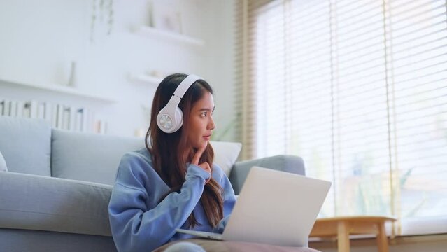 Young Asian Woman Having a Video Call on Laptop in a Cozy Home Office - Remote Work and Technology Concept