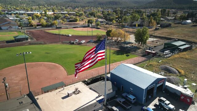 Aerial tilt up on USA flag at baseball diamond in small town of Williams Arizona