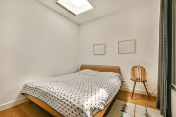 a bedroom with white walls and wood flooring the room has a bed, chair, window, and skylight