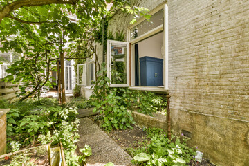 the outside of a house with plants growing in front and an open window on the other side of the...