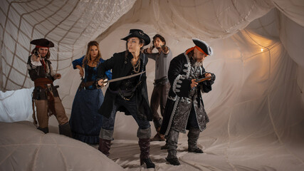A merry band of pirates, a group photo in carnival costumes, corsairs on the background of sails - 673012361