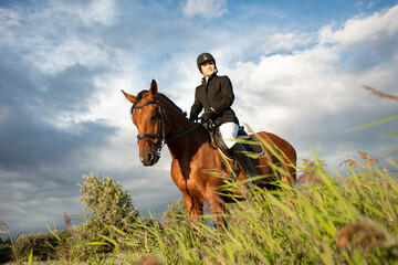 Horsewoman in equestrian sports gear, riding a horse, against an expressive sky, horseback riding...