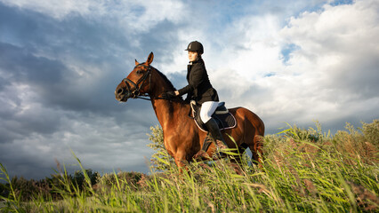 Horsewoman in equestrian sports gear, riding a horse, against an expressive sky, horseback riding...