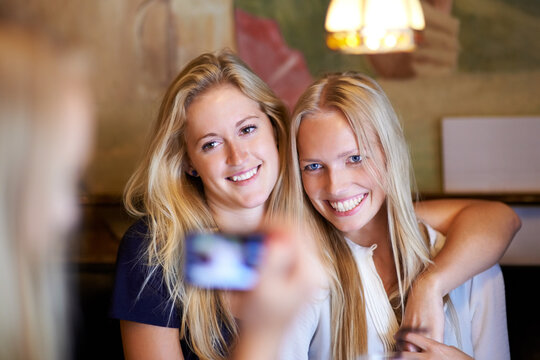 Friends, women and picture with cafe, smile and smartphone with digital app, pose and memory. People, restaurant and girls embrace, photography or happiness with joy, social media or bonding together