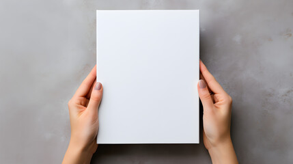 Mockup design template with a blank magazine being held by female hands against a gray background,