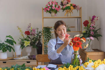 Floristry concept, Woman florist arranged colorful gerberas in glass vase for client at flower shop