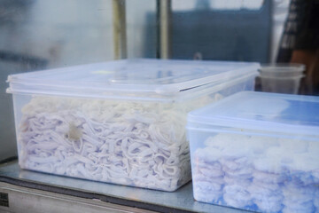 Raw noodle dough resting in a plastic box, ready to be transformed into delicious pasta