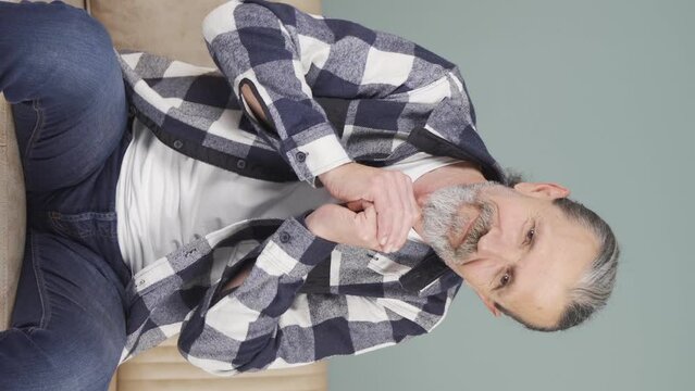 Vertical video of Old man apologizing looking at camera.