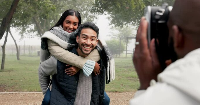 Couple, piggyback and photographer at park to take picture, bonding and smile on holiday in winter fog. Interracial, man and woman taking photo on vacation for happy memory, love and care in nature