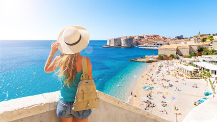 Woman tourist looking at panoramic view of Dubrovnik city and beach- Croatia - obrazy, fototapety, plakaty