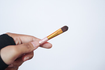 Hand model holding a a set of makeup brushes with a white background for cosmetic advertising