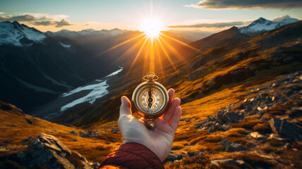 Hand holding a compass on the mountain in a bright morning.