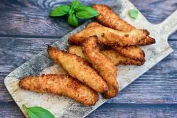  Crispy  deep fried home made    chicken strips Breaded  with  almond flour chicken  breast fillets  with chilly peppers and fresh   basil on wooden rustic background. Ketogenic diet food