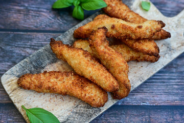  Crispy  deep fried home made    chicken strips Breaded  with  almond flour chicken  breast fillets  with chilly peppers and fresh   basil on wooden rustic background. Ketogenic diet food