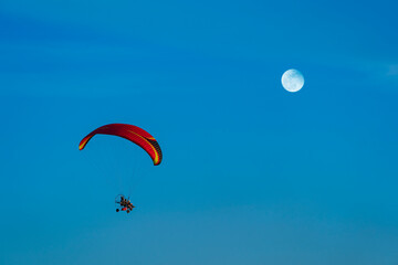 Flying with paramotor in the blue sky - Man riding paramotor in the blue sky background.