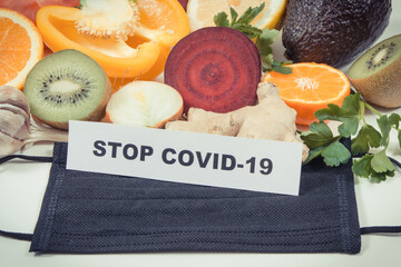 Inscription stop covid-19, fresh fruits with vegetables and protective mask. Source natural...