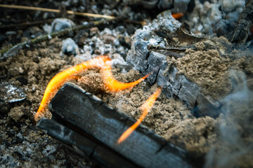 A fire burns in a campfire with a red fire in the background.