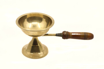 vintage golden brass diya oil lamp or vilakku with handle traditionally used for pooja rituals in temples of india isolated in a white background