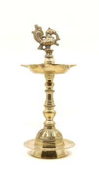 a vintage indian samai or vilakku, an oil lamp with a peacock bird emblem used to light fire and pray to god during religious events and rituals isolated