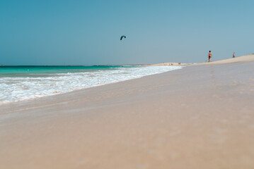 Fototapeta na wymiar Weiter Strand mit Ocean und Kitesurfer im Hintergrund am Horizont 