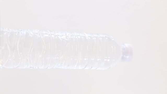 Close up one plastic bottle of drinking still water rotating over white background