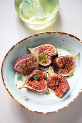 Fresh torn fig fruits with greek yogurt served in a green bowl, vertical shot, middle close-up, selective focus