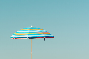 blau gestreifter Sonnenschirm am Strand  