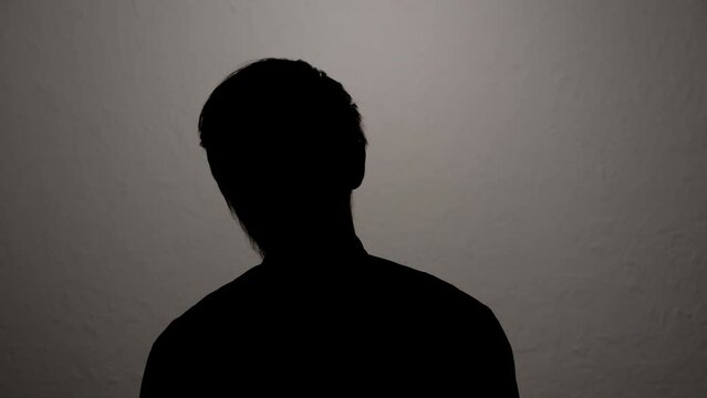 Silhouette of man hiding identity while giving anonymous interview on camera.