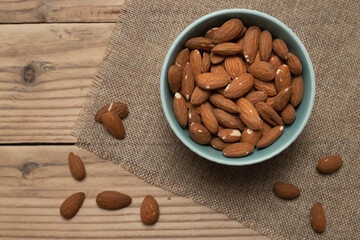 Almonds in a bowl on a wooden background.