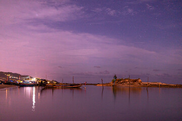 Summer beach with blue water and purple sky at the sunset. 