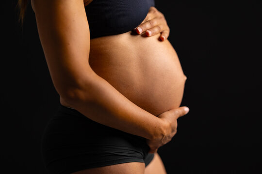 Close-up of beautiful pregnant woman with her hands on her bare belly