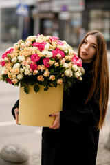 Pretty woman holds a huge bouquet of roses in her hands