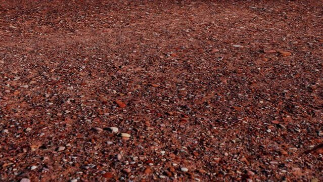 Red ground reminiscent of the Martian surface with small stones. Video about land exploration with copy space. Wallpapers Footage in Ultra HD 4k.
