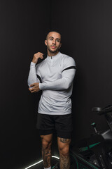 Fototapeta premium Chico joven musculado posando con ropa deportiva en gimnasio casero