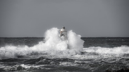 Fototapeta na wymiar Lighthouse storm - mangiabarche lighthouse during a winter swell in Calasetta in southern Sardinia